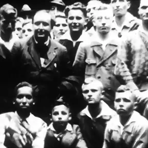 Stilisierter Ausschnitt eines monochromen, historischen Fotos zeigt einen Schwarzen inmitten einer Gruppe weißer Jungen und Männer.