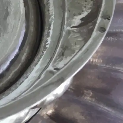 Stilisierter Ausschnitt des Bildes einer silbernen Taufschale mit gewelltem Rand.